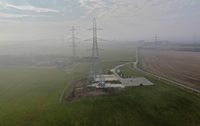 A metal transmission tower without any connections. In the background are a series of other towers forming an overhead line.