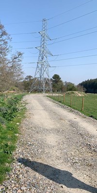 A metal transmission tower at the end of a gravel road.