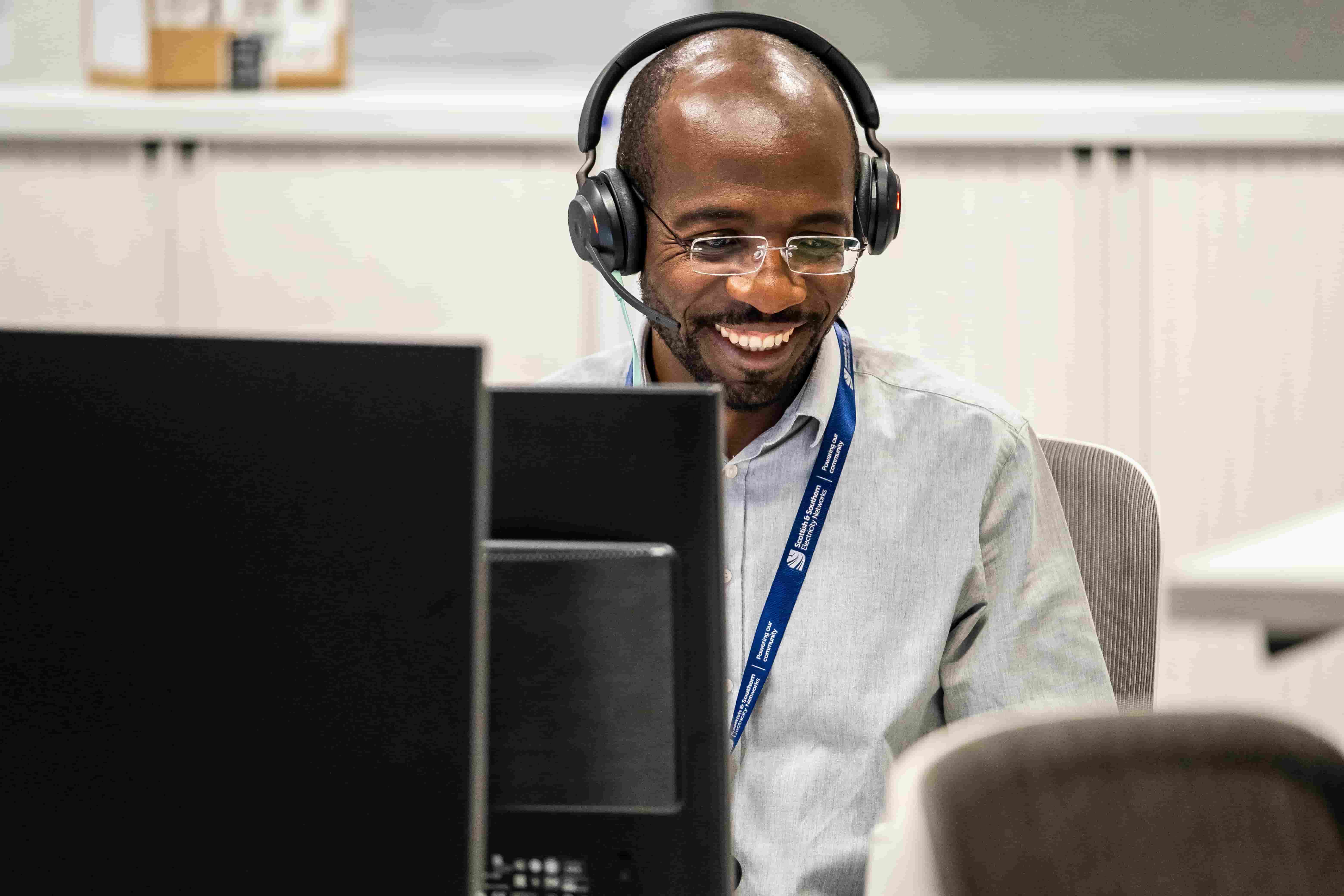 A colleague sat at their work desk taking a call on their headset 