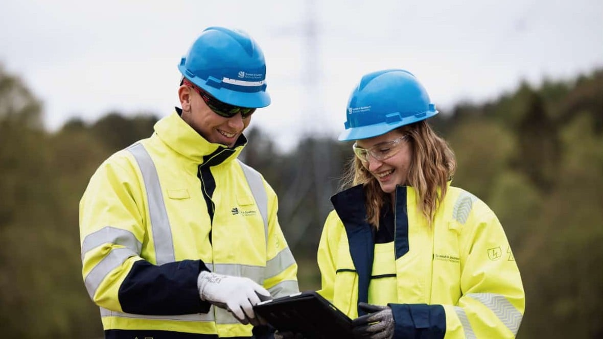 Two SSEN Transmission team members smiling while looking at a clip board
