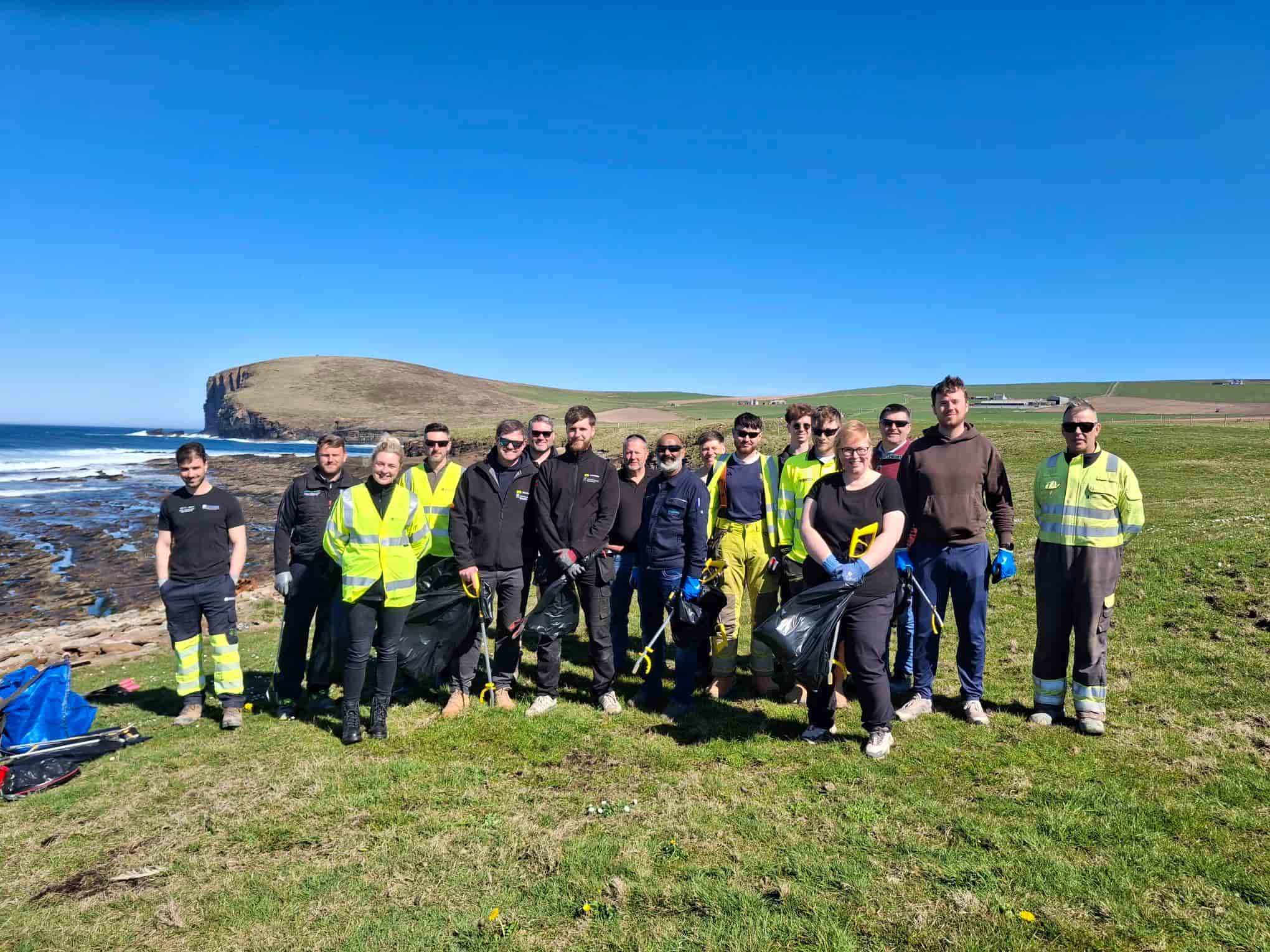 Volunteers with litter picking equipment by the beach.