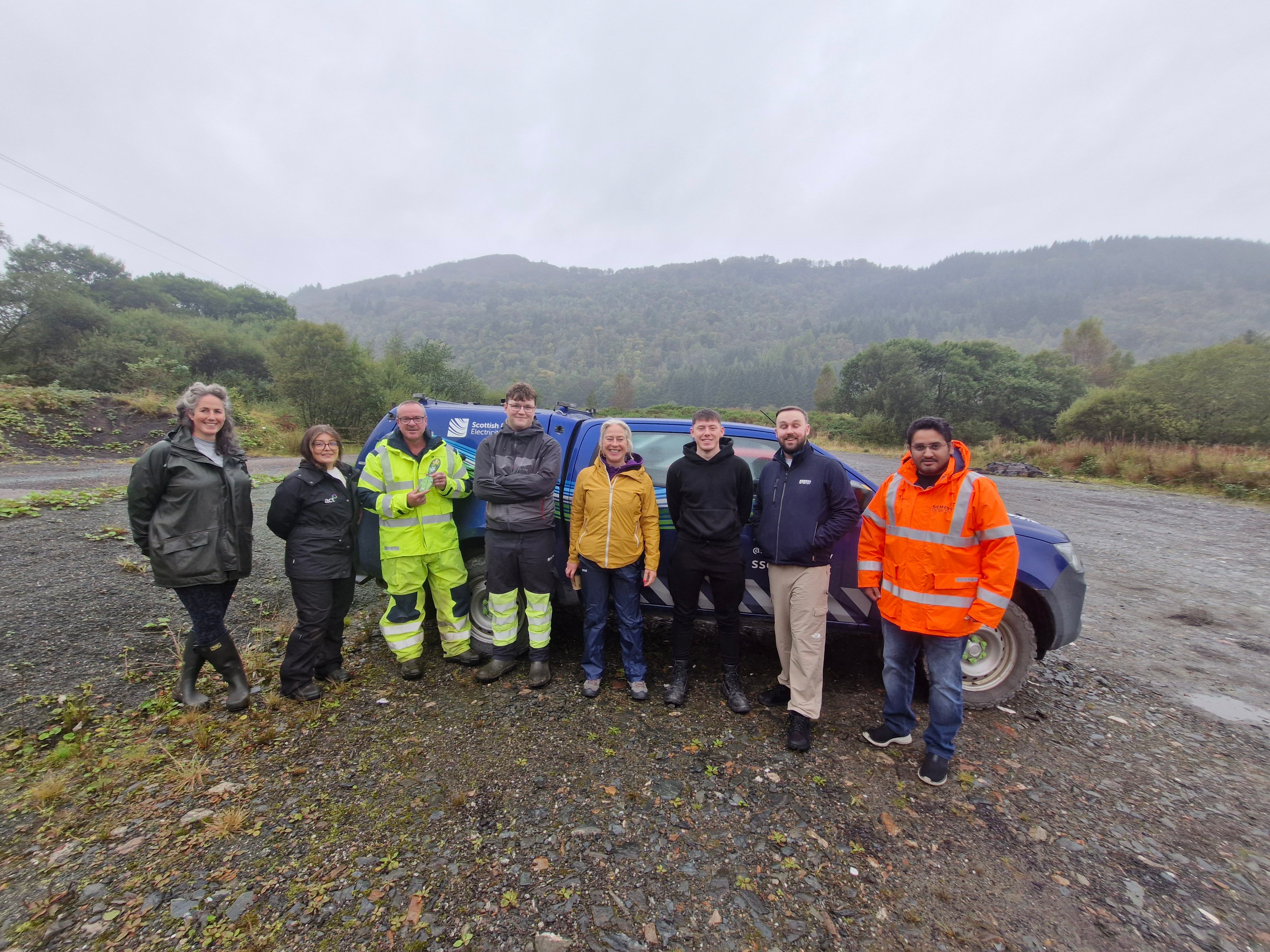 A group of six volunteers stood in front of a company vehicle