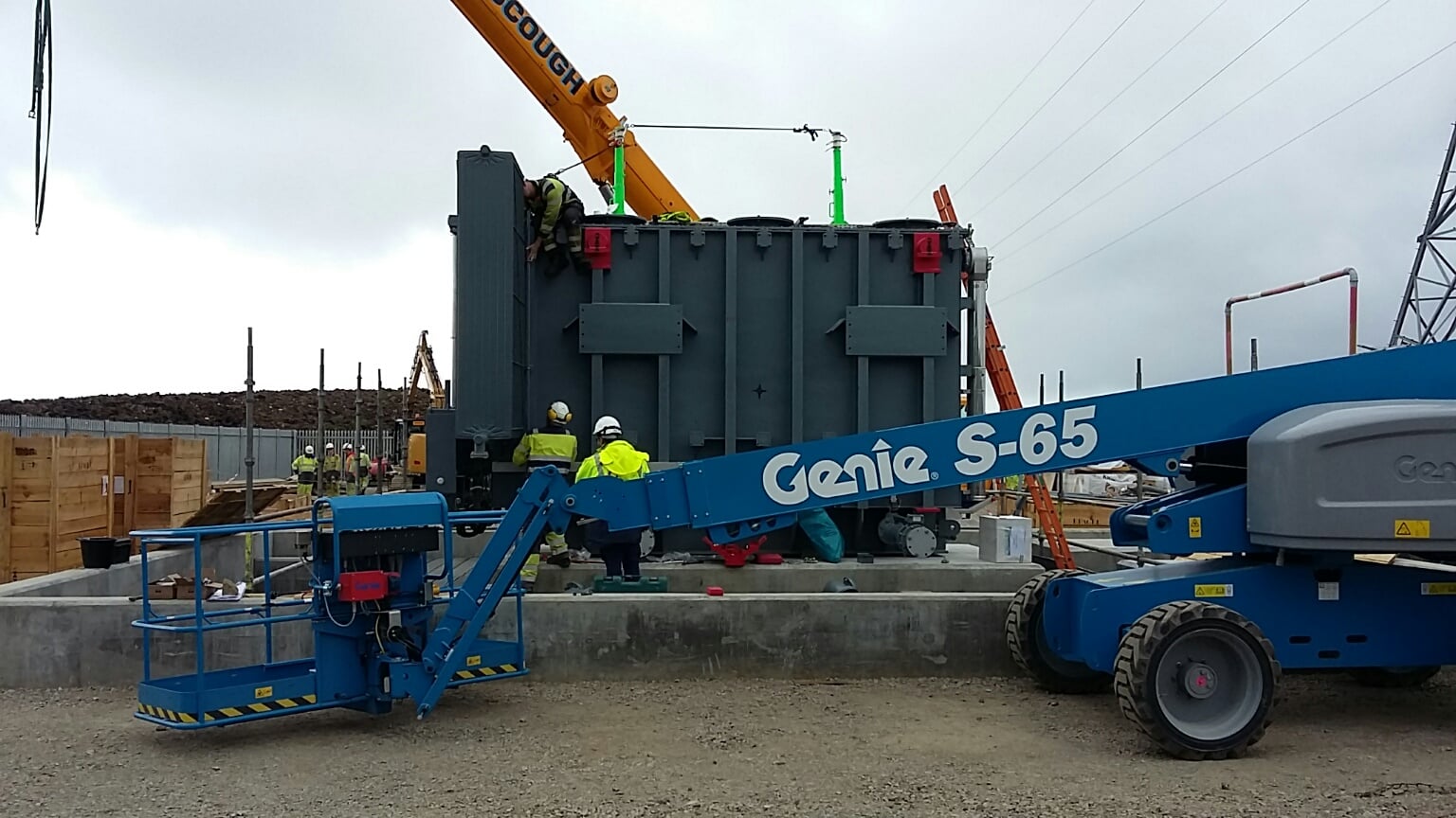 Transformer assembly A large section of substation infrastructure mounted on a concrete platform surrounded by construction vehicles and contractors in PPE.