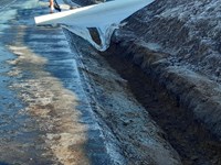 An excavated trench next to a surfaced road.