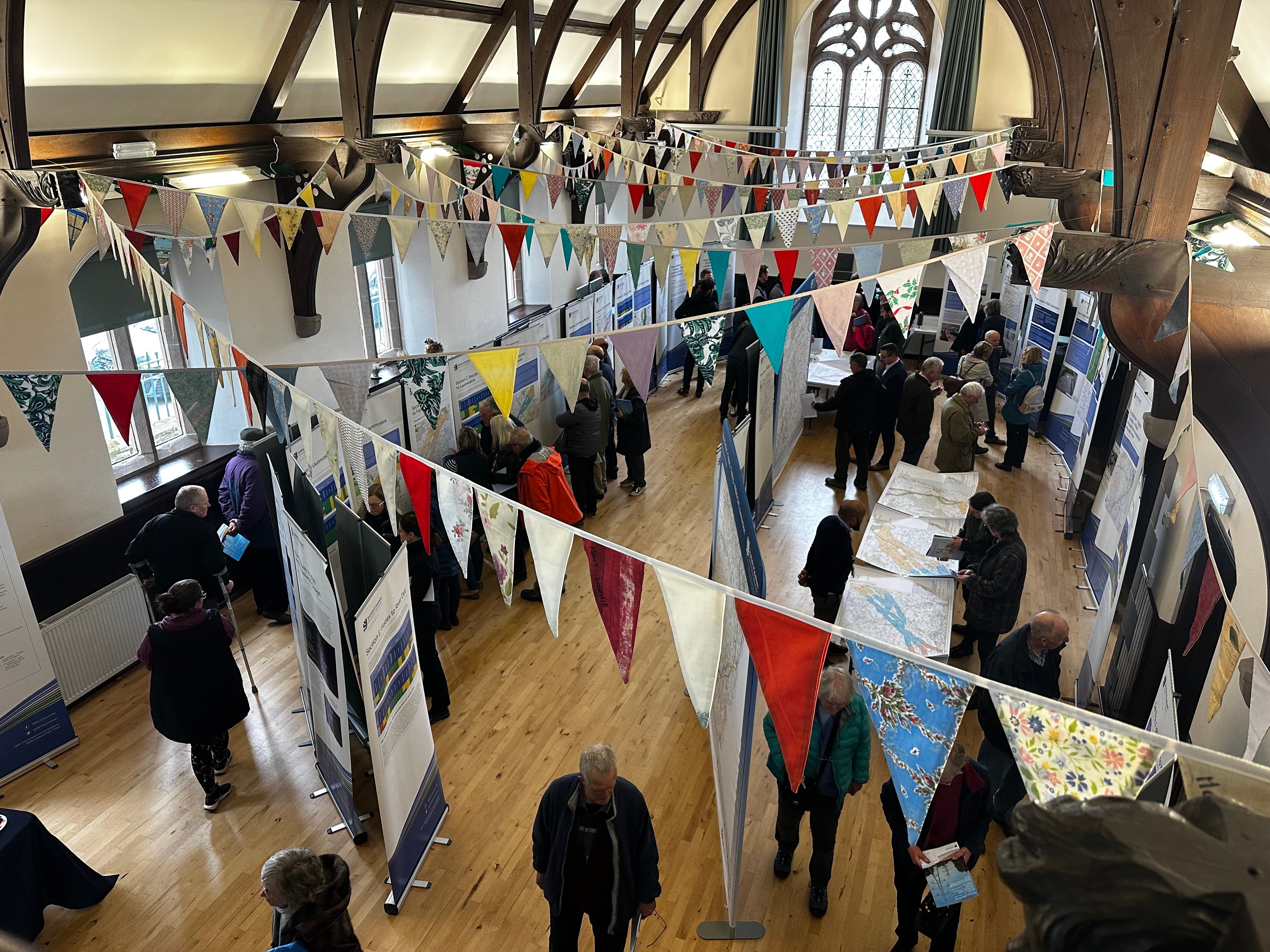 Members of the public and SSEN Transmission employees examining project posters in a hall.