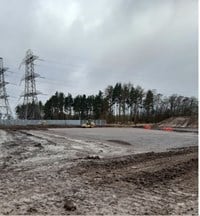 A gravel and dirt area next to a substation.