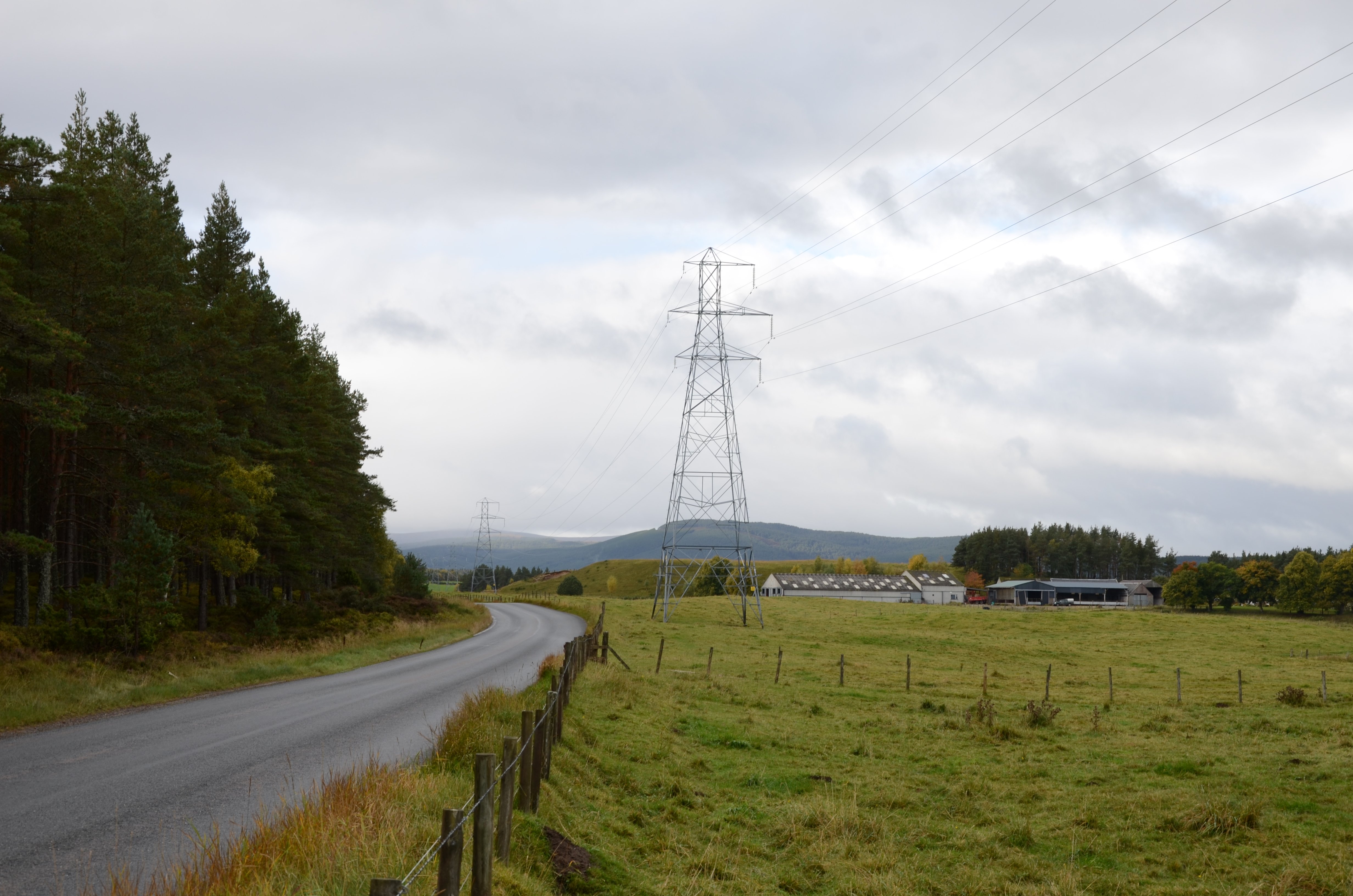 Nethy Bridge Metal transmission towers forming an overhead line over fields next to a road.
