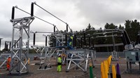 Contractors in PPE atop and nearby substation infrastructure.