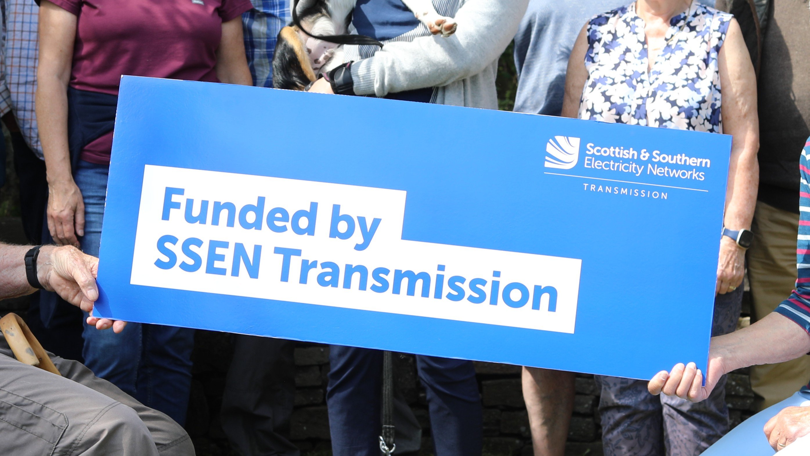 A community holding a sign that says "Funded by SSEN Transmission"