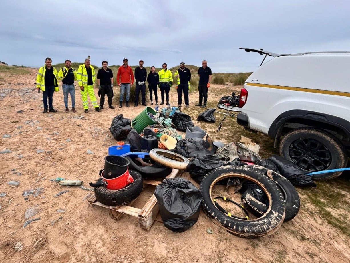 A group of volunteers standing behind rubbish collected during the Rattray Head Beach clean