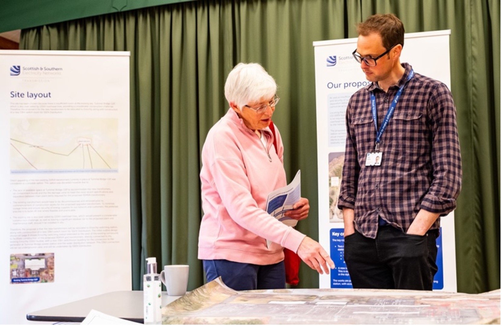 A member of the community is speaking with a member of the SSEN Transmission team and asking questions about a proposal during a consultation event.