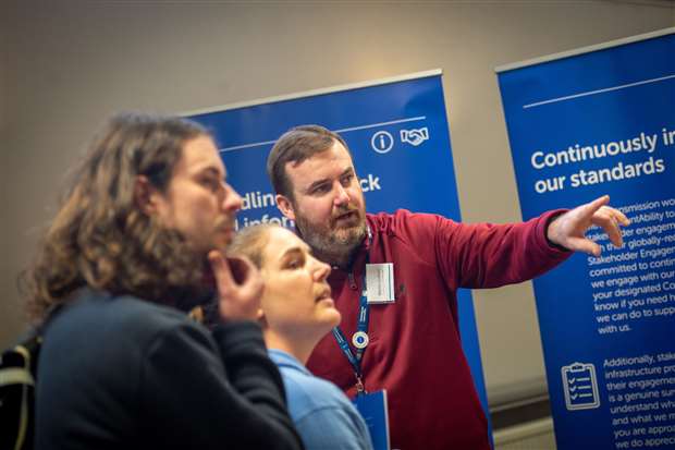 An SSEN Transmission employee and members of the public examining project posters.