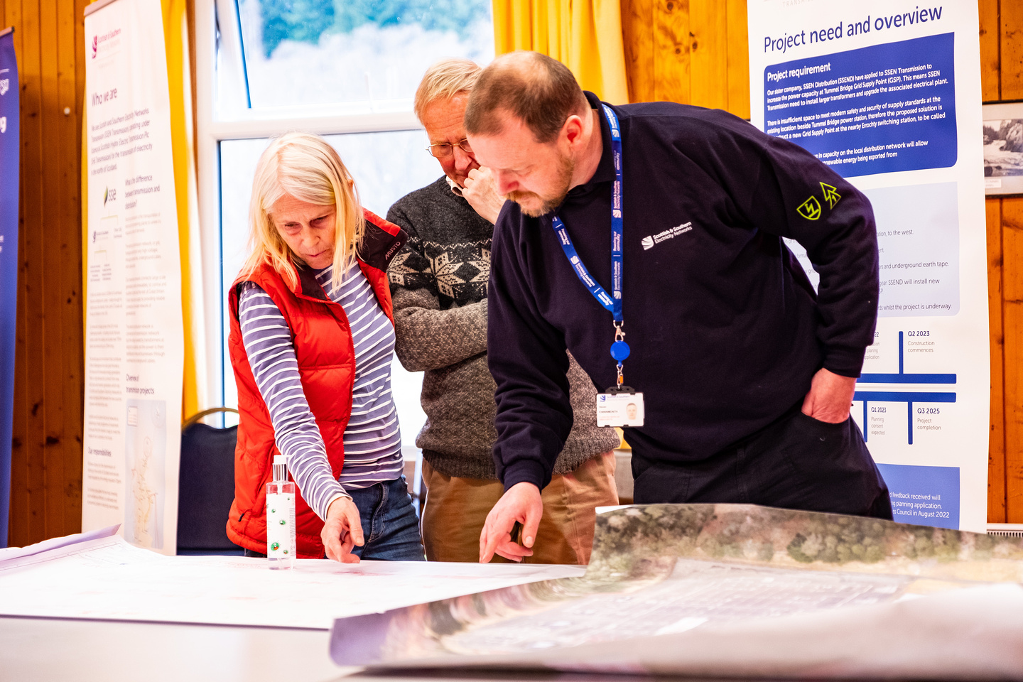 Two members of the local community are reviewing plans with an SSEN Transmission employee at an engagement event