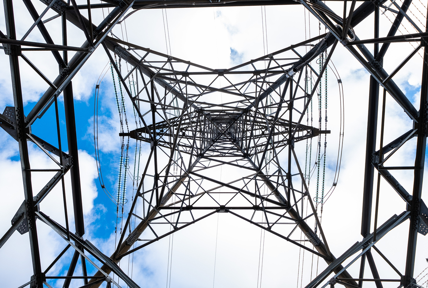 The underneath of a transmission tower against a blue sky