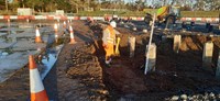 A contractor standing in an excavated area full of vertical reinforced concrete pillars.