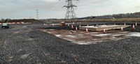 A dirt area with two concrete slabs. Metal fittings extend out of the concrete.