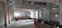 Contractor wearing PPE in the interior of a metal-framed building.