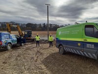 SSEN Transmission employees in PPE next to SSEN Transmission vehicles. Behind them is a tall wooden pole with a horizontal beam at the top.