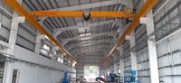 Interior of a metal-framed building with an orange horizontal crane arm built into the ceiling structure.