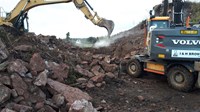 Excavators next to an area covered with rocks.