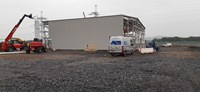 Metal-framed building with construction vehicles on a construction site.