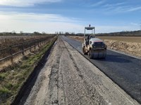 A surfacing vehicle parked on a newly surfaced section of an excavated dirt road.