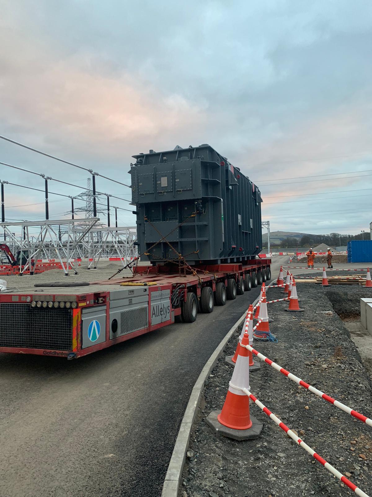 A rectangular section of substation infrastructure on a flatbed trailer at a substation.