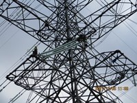 Two people in PPE on a metal transmission tower.