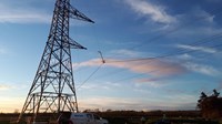 A metal transmission tower, below contractors in PPE stand near a Balfour Beatty vehicle.