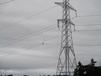 Transmission cables suspended from a metal transmission tower.