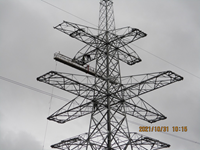 Contractors in PPE atop a metal transmission tower. A date in the corner reads "2021/10/31 10:15".