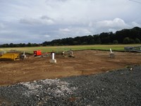 Four concrete sections embedded in the ground. Metal supports emerge from the concrete.