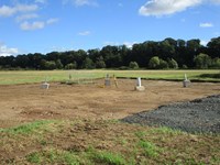 Four concrete sections embedded in the ground. Metal supports emerge from the concrete.