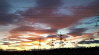 Metal transmission towers silhouetted against the sunset.