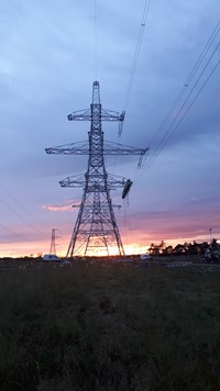 A substation under construction, a line of metal transmission towers are present in the background.