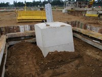 A large concrete section emerging from an excavated area. A metal support emerges from the concrete.