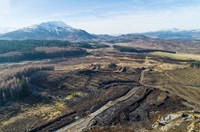 An aerial view of an area of rural land with mountains in the background, the area has several dirt roads crossing it.