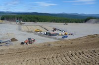 A fenced area on a flat rocky platform, surrounded by construction vehicles.