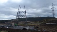 The base of a metal transmission tower, other tower sections lie nearby.