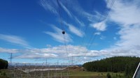 A contractor in PPE working on overhead lines passing over a  scaffolding structure.