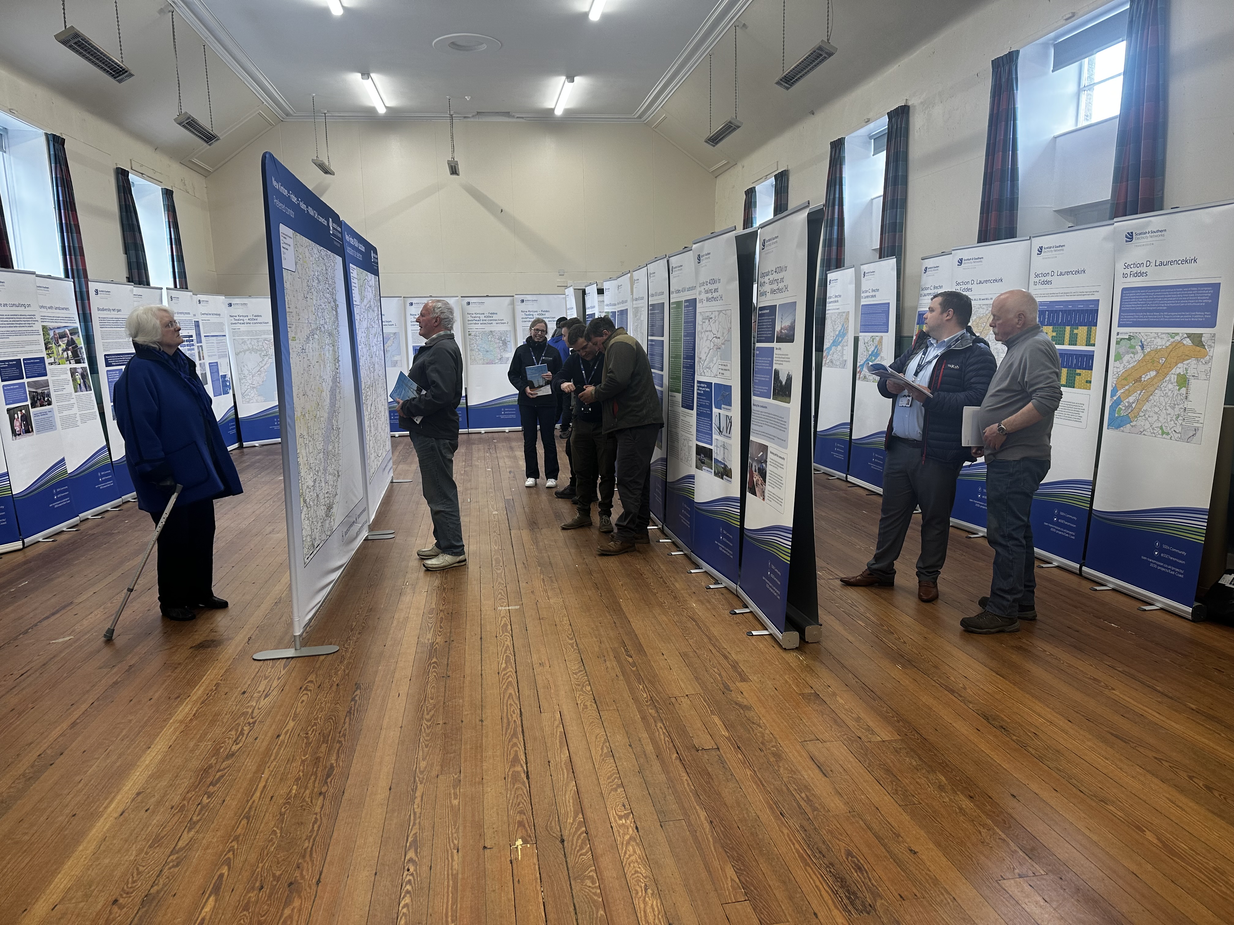 Members of the public and SSEN Transmission employees examining project posters in a hall.