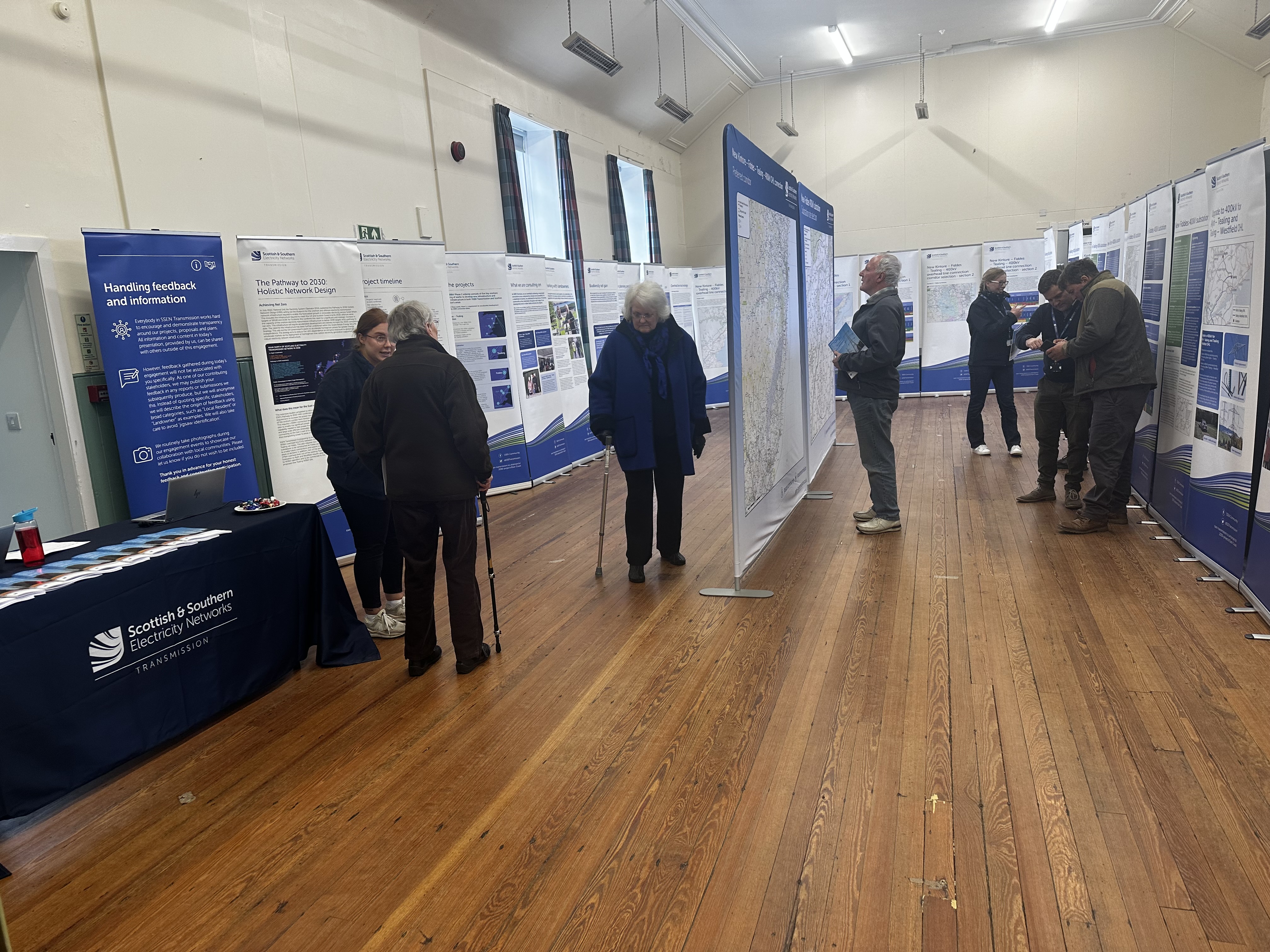 Members of the public and SSEN Transmission employees examining project posters in a hall.