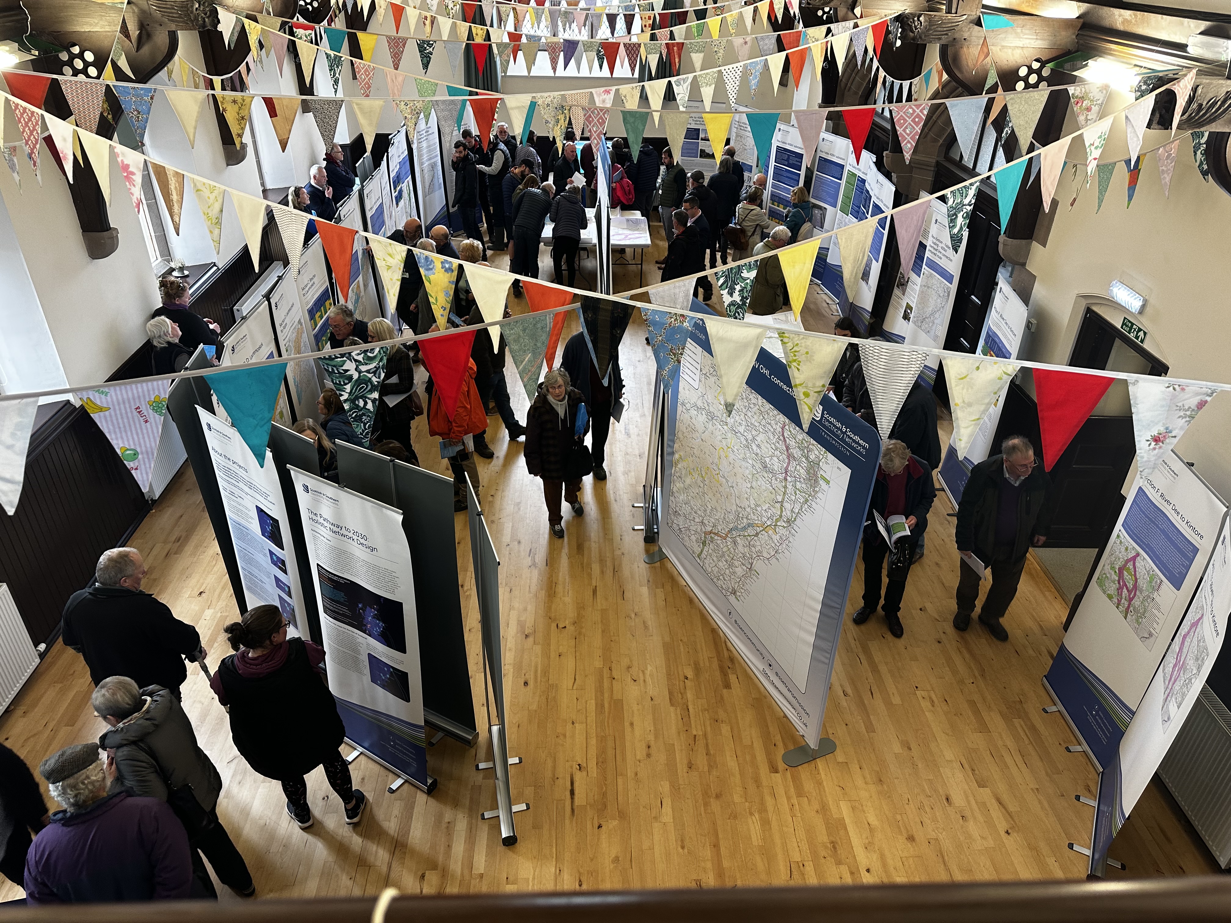 Members of the public and SSEN Transmission employees examining project posters in a hall.