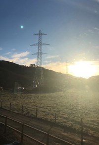 Metal transmission towers in front of a sunset.
