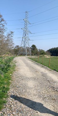 A metal transmission tower at the end of a gravel road.
