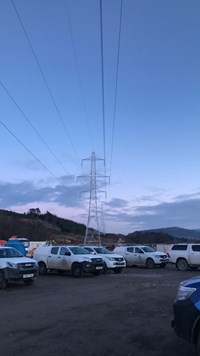 Metal transmission towers in front of a sunset.