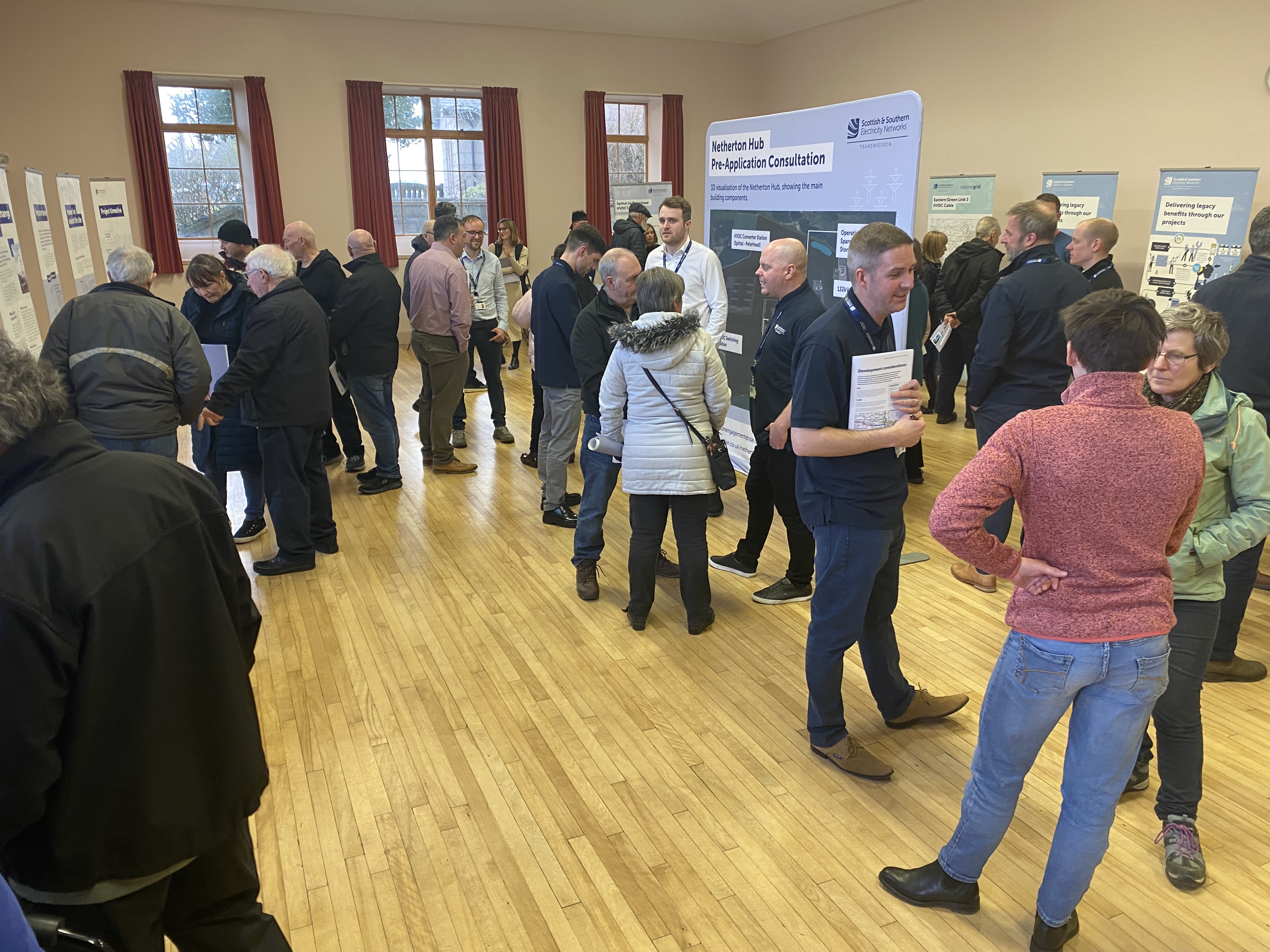 Members of the public with SSEN Transmission employees in a hall with project posters.