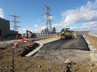 Road surface being laid down by construction vehicles on a gravel section of a substation construction site.