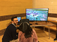 A primary school aged child using Virtual Reality equipment. On a screen a simulated model of buildings are visible.