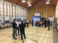 Primary school aged children and Staff with SSEN Transmission employees standing in a hall next to a large poster titled "Orkney Infrastructure Project" "The South Section." Other smaller posters are present along the walls.